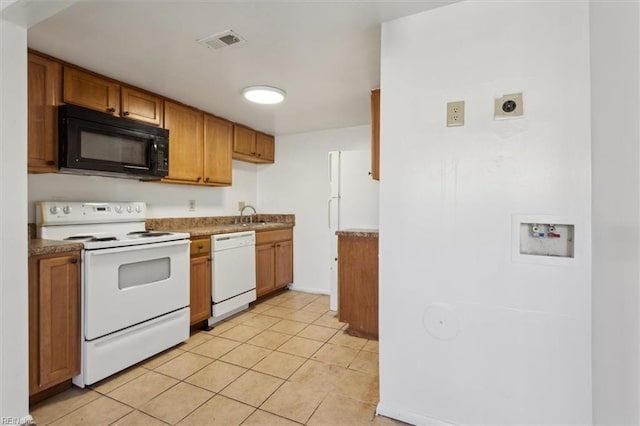 kitchen featuring sink, light tile patterned floors, and white appliances