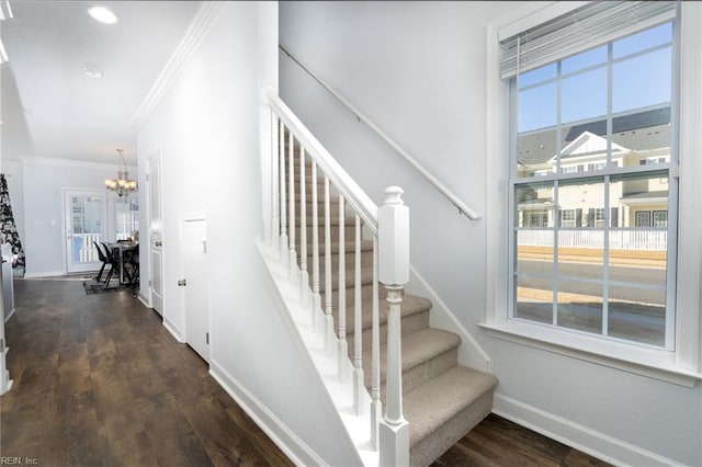 staircase featuring ornamental molding, a chandelier, and hardwood / wood-style floors