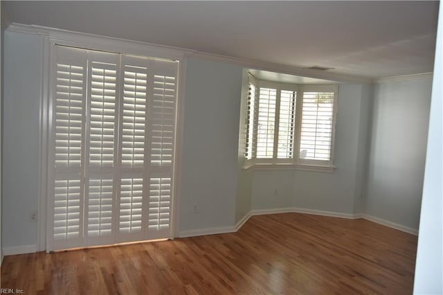 empty room with crown molding and wood-type flooring