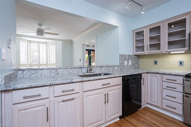 kitchen with tasteful backsplash, black dishwasher, sink, light stone counters, and light wood-type flooring