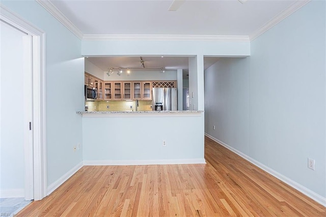 kitchen featuring appliances with stainless steel finishes, kitchen peninsula, crown molding, light stone countertops, and light hardwood / wood-style flooring