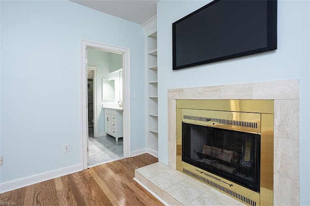 interior details with hardwood / wood-style floors, built in features, and a tile fireplace