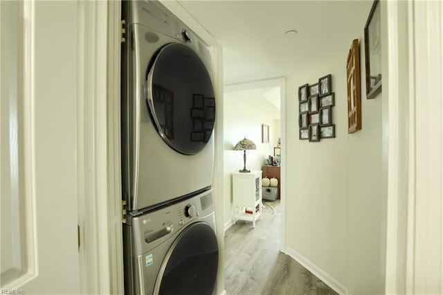 laundry room with stacked washer / dryer and light hardwood / wood-style floors