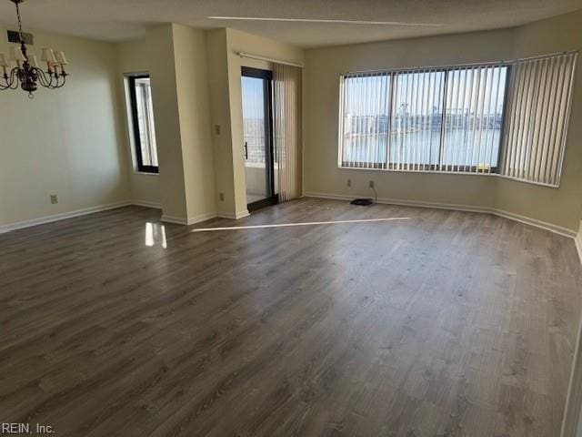 unfurnished room with an inviting chandelier and dark hardwood / wood-style floors