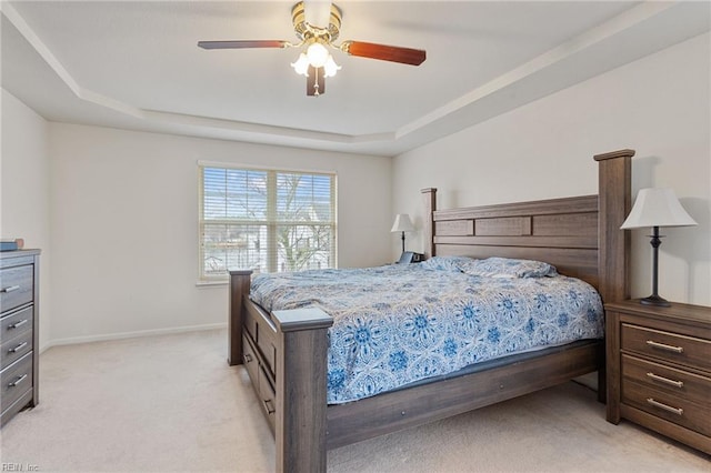 bedroom with a tray ceiling, light colored carpet, and ceiling fan