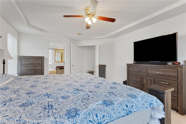 bedroom with a raised ceiling, ensuite bathroom, and ceiling fan