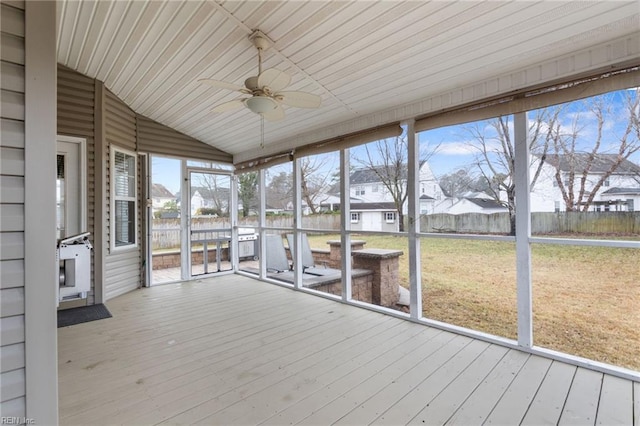 unfurnished sunroom with vaulted ceiling, a wealth of natural light, and ceiling fan