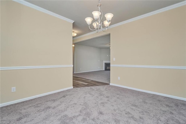 empty room featuring dark colored carpet, ornamental molding, and a notable chandelier