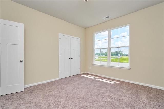 unfurnished bedroom featuring light colored carpet and a closet