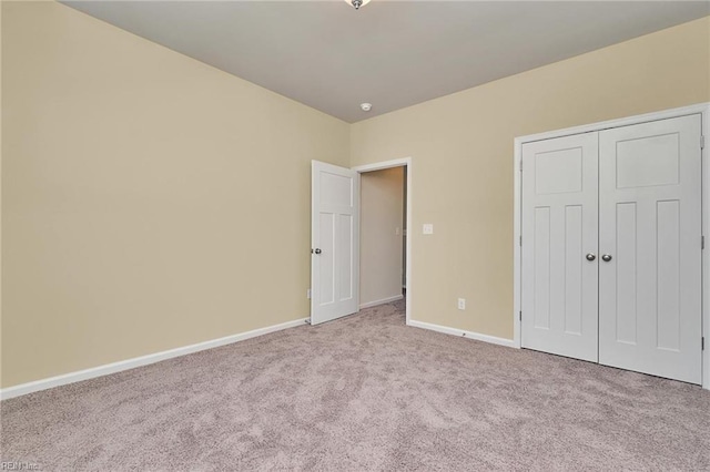 unfurnished bedroom featuring light colored carpet and a closet