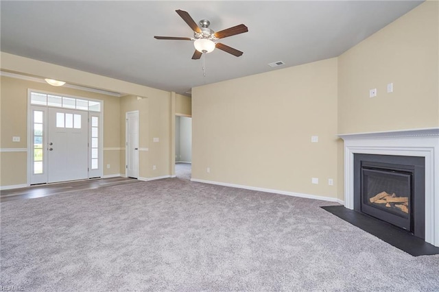 unfurnished living room with ceiling fan and dark colored carpet