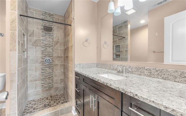 bathroom featuring tiled shower and vanity