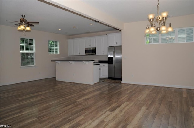 kitchen featuring a kitchen bar, white cabinetry, hanging light fixtures, appliances with stainless steel finishes, and dark hardwood / wood-style floors