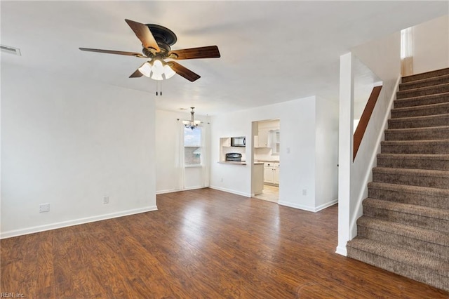 unfurnished living room featuring ceiling fan with notable chandelier and dark hardwood / wood-style flooring