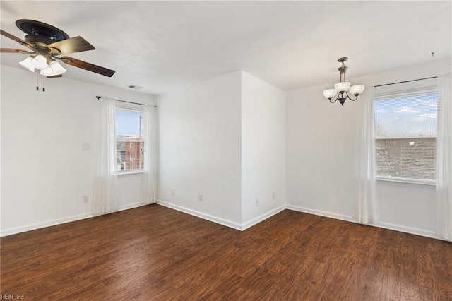 empty room featuring ceiling fan with notable chandelier and dark wood-type flooring