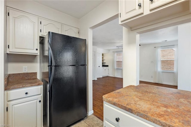 kitchen with black refrigerator and white cabinets