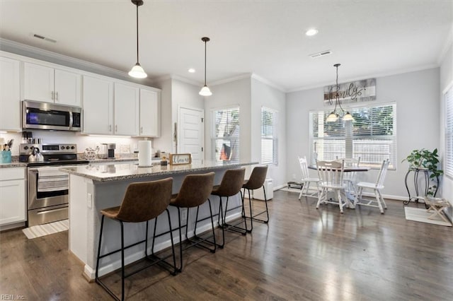 kitchen with white cabinetry, appliances with stainless steel finishes, a center island, and pendant lighting