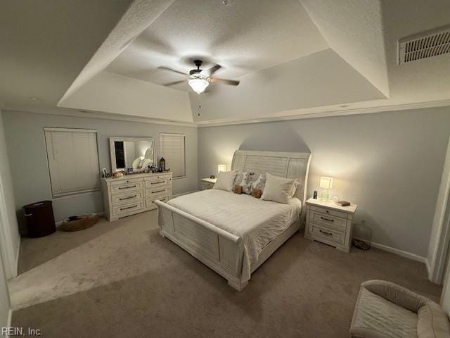 bedroom with a raised ceiling, light colored carpet, and ceiling fan