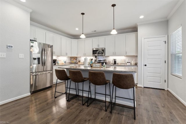 kitchen with white cabinetry, appliances with stainless steel finishes, stone countertops, and a center island with sink