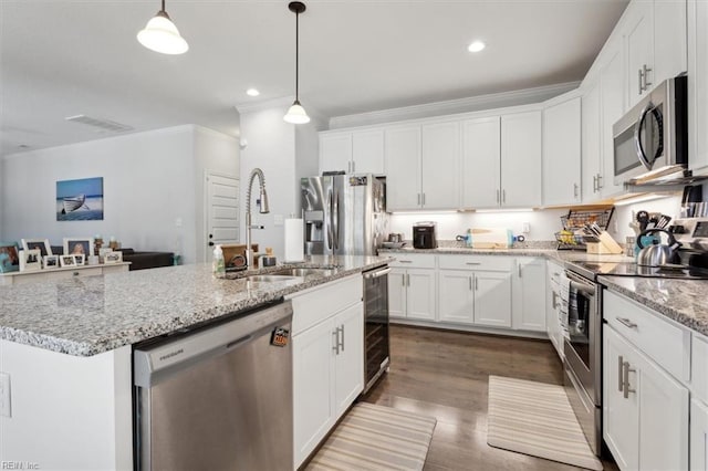 kitchen with sink, hanging light fixtures, stainless steel appliances, an island with sink, and white cabinets