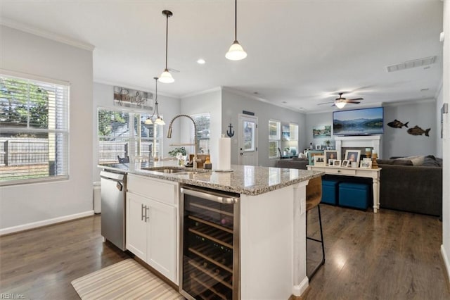 kitchen with wine cooler, sink, pendant lighting, a kitchen island with sink, and white cabinets