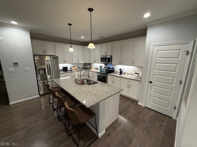 kitchen with sink, appliances with stainless steel finishes, a kitchen breakfast bar, an island with sink, and white cabinets