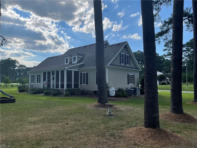 back of house with central air condition unit, a sunroom, and a lawn