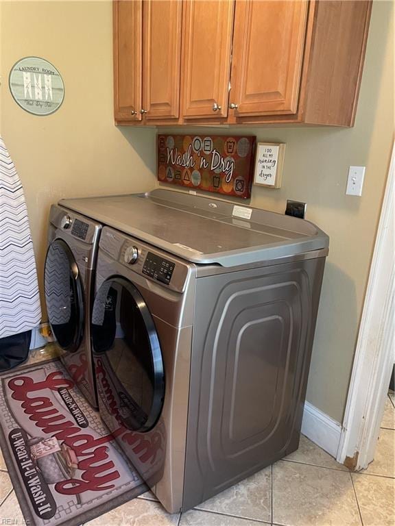 laundry area with cabinets, light tile patterned flooring, and washer and clothes dryer