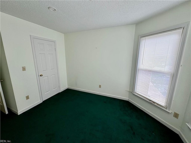 empty room with dark colored carpet and a textured ceiling