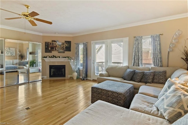 living room featuring ceiling fan, ornamental molding, and light hardwood / wood-style floors