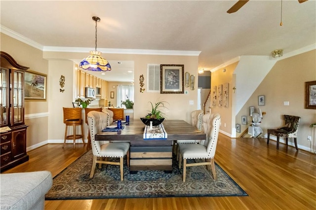 dining room with crown molding, wood-type flooring, and ceiling fan