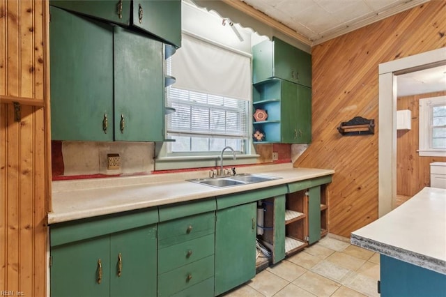 kitchen featuring wooden walls, sink, backsplash, light tile patterned floors, and green cabinetry