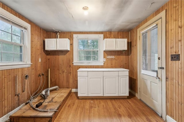 interior space featuring white cabinetry, wood walls, and light hardwood / wood-style flooring