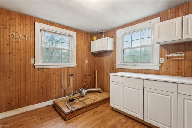 interior space with white cabinetry, tile countertops, light hardwood / wood-style floors, and a healthy amount of sunlight