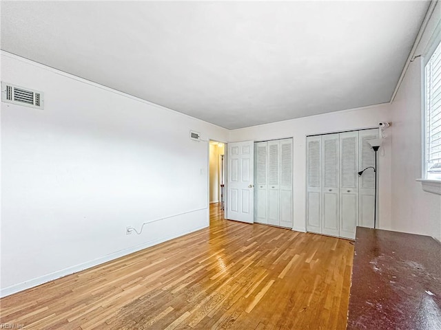 unfurnished bedroom featuring light hardwood / wood-style floors and multiple closets