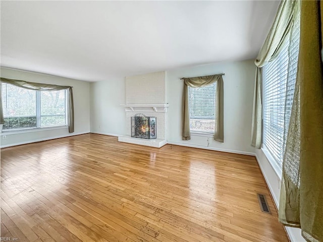 unfurnished living room with a fireplace and light wood-type flooring