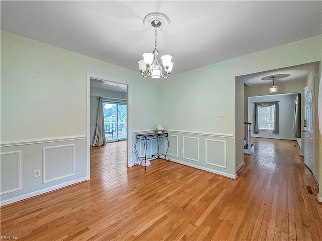 unfurnished dining area featuring a chandelier and light hardwood / wood-style flooring