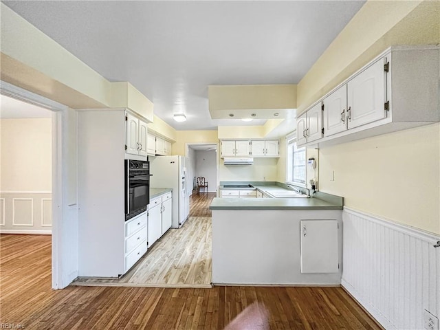 kitchen with light hardwood / wood-style flooring, oven, white refrigerator with ice dispenser, white cabinets, and kitchen peninsula