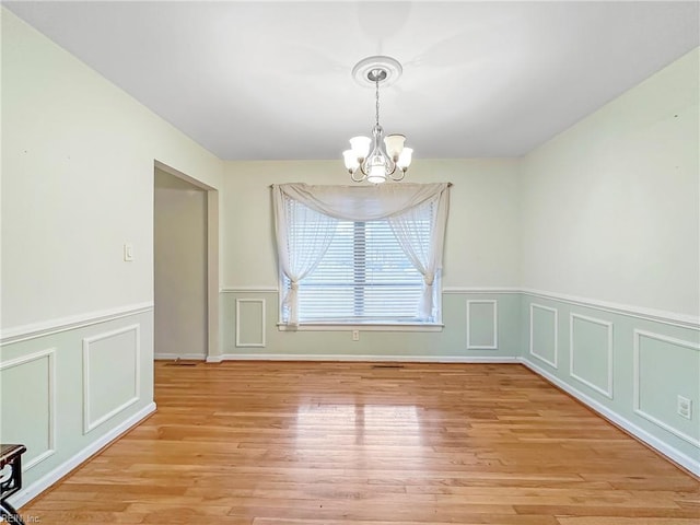 unfurnished dining area with light hardwood / wood-style floors and a notable chandelier