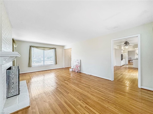 unfurnished living room featuring a brick fireplace and light hardwood / wood-style flooring