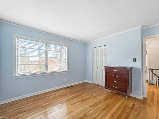 unfurnished bedroom featuring ornamental molding, light wood-type flooring, and a closet