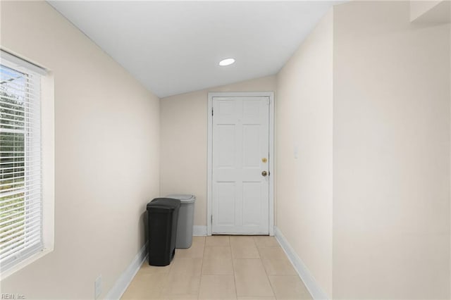 corridor with plenty of natural light, vaulted ceiling, and light tile patterned floors