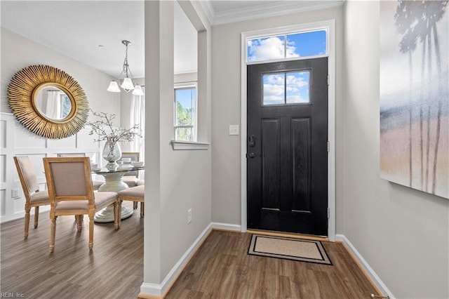 entryway featuring wood-type flooring, ornamental molding, and a chandelier