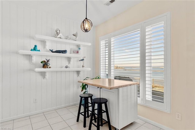 bar featuring pendant lighting, white cabinetry, and light tile patterned floors