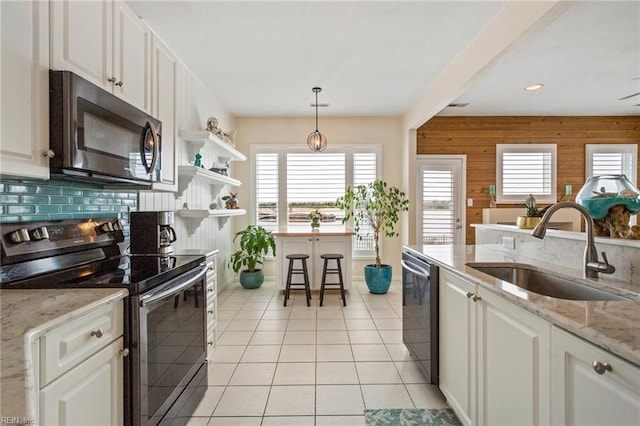 kitchen with decorative light fixtures, white cabinetry, sink, stainless steel appliances, and light stone countertops