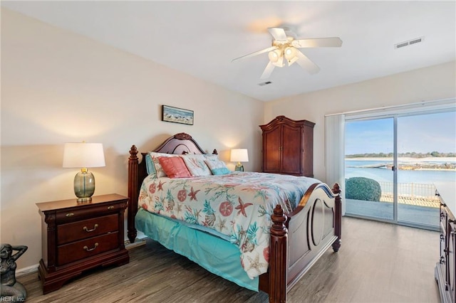 bedroom with hardwood / wood-style floors, a water view, access to outside, and ceiling fan