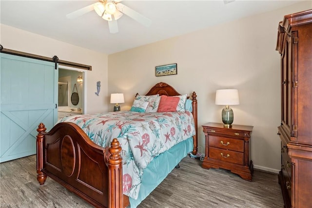 bedroom with connected bathroom, wood-type flooring, a barn door, and ceiling fan