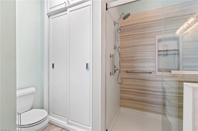 bathroom featuring a shower with shower door and toilet