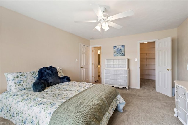 bedroom with a spacious closet, light colored carpet, ceiling fan, and a closet