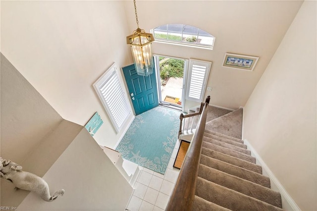 foyer entrance featuring light tile patterned floors and a towering ceiling